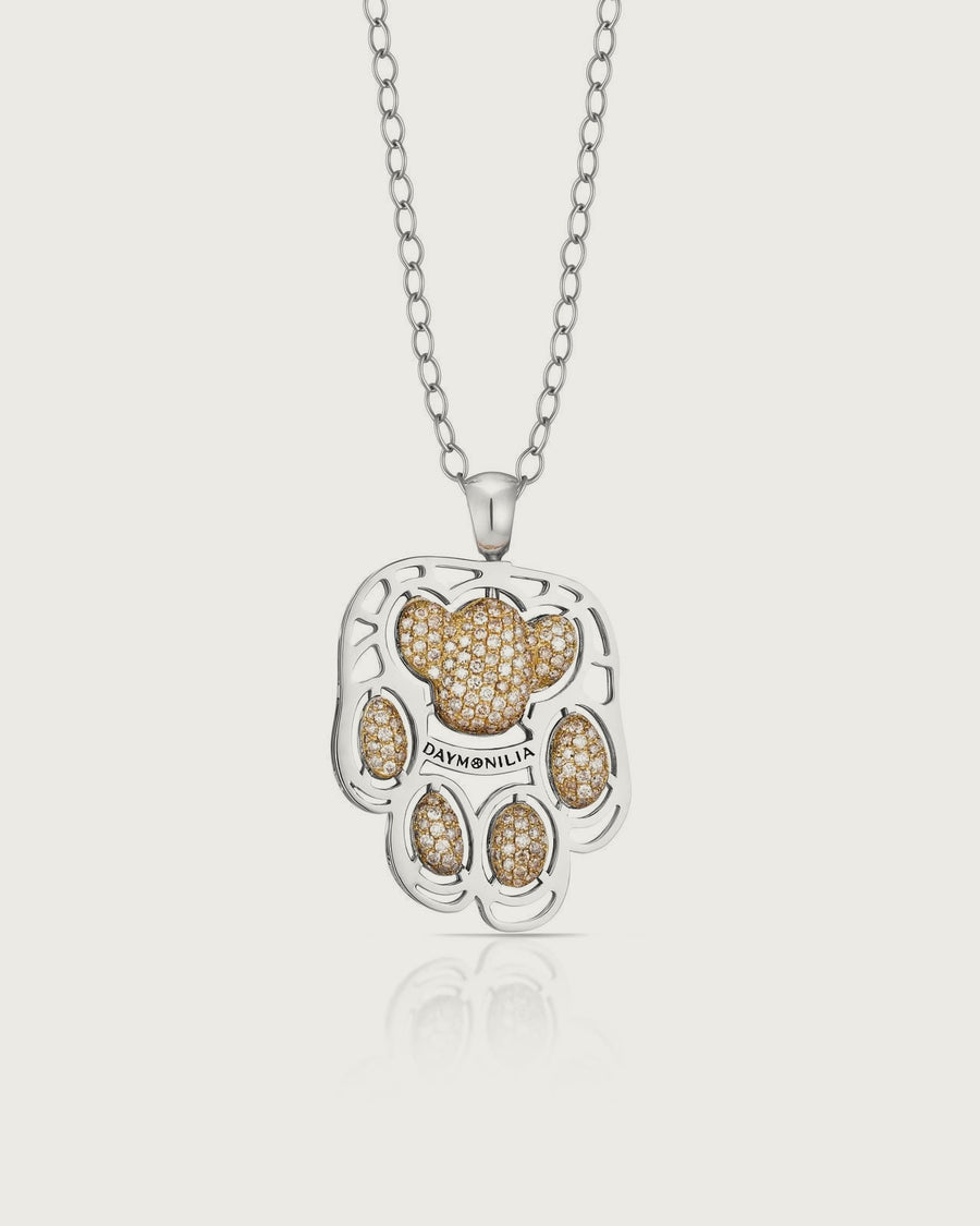 Manto sulla sua catena: il telaio traforato in oro bianco, i cuscinetti in oro con pavé di diamanti naturali color miele, la fascia incisa Daymonilia.
