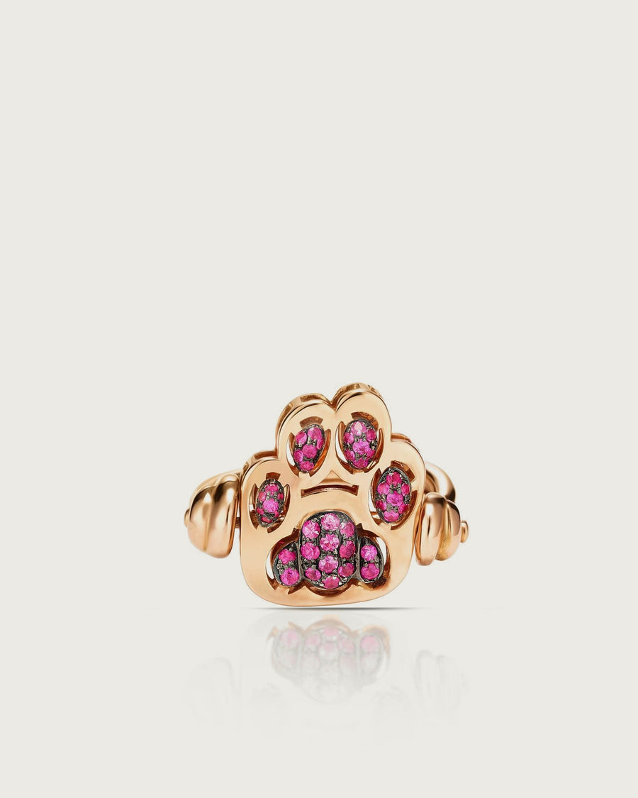 Fusa di fronte: l'anello in oro rosa con la zampa di rubini, su fondo osso.