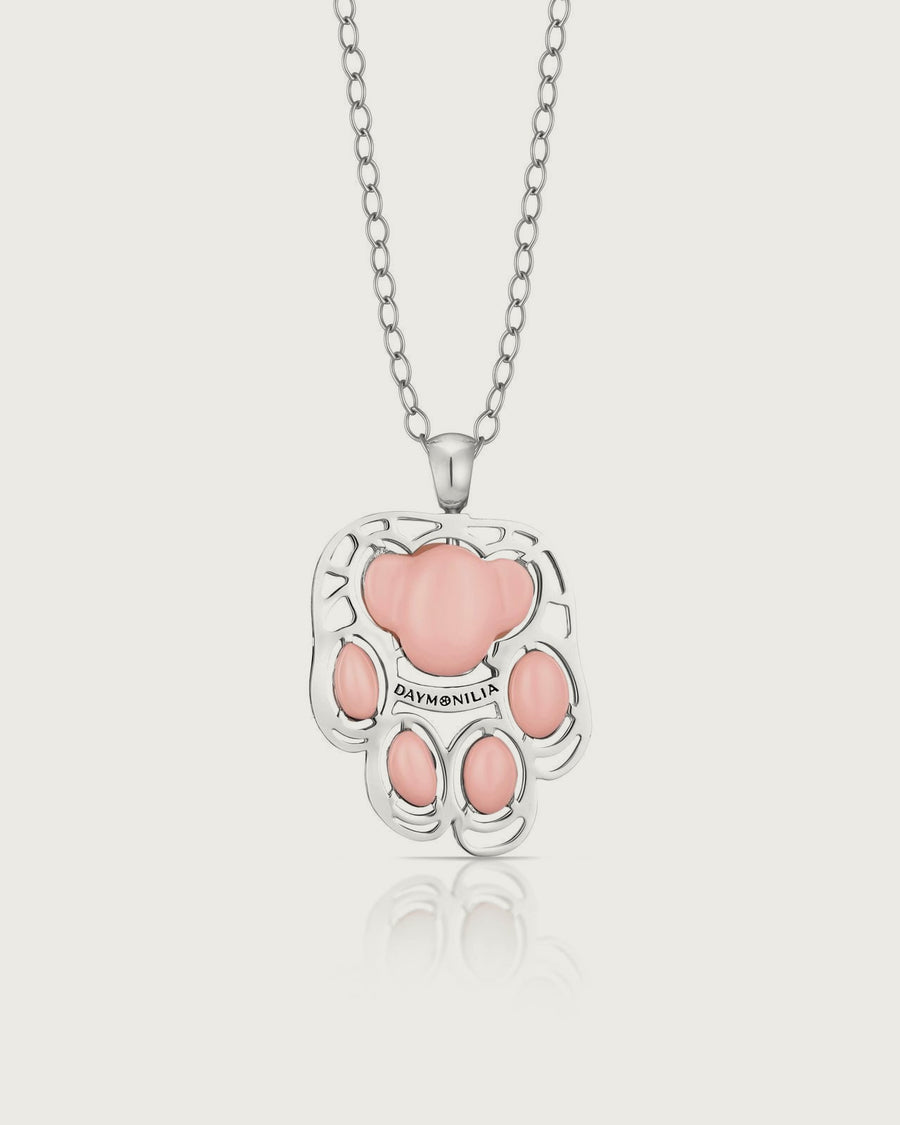 Palmo di Daymonilia: pendente zampa in argento con cinque cuscinetti rosa in composto vitreo, appeso alla sua catena a maglie ovali, su fondo osso.