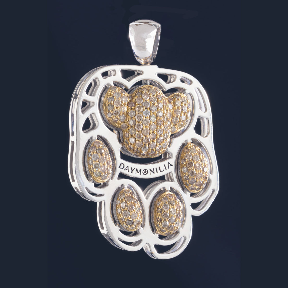 Manto di Daymonilia visto di fronte: telaio traforato in metallo bianco, cinque cuscinetti in oro con pave' di diamanti color miele, la fascia incisa Daymonilia, sul nero.