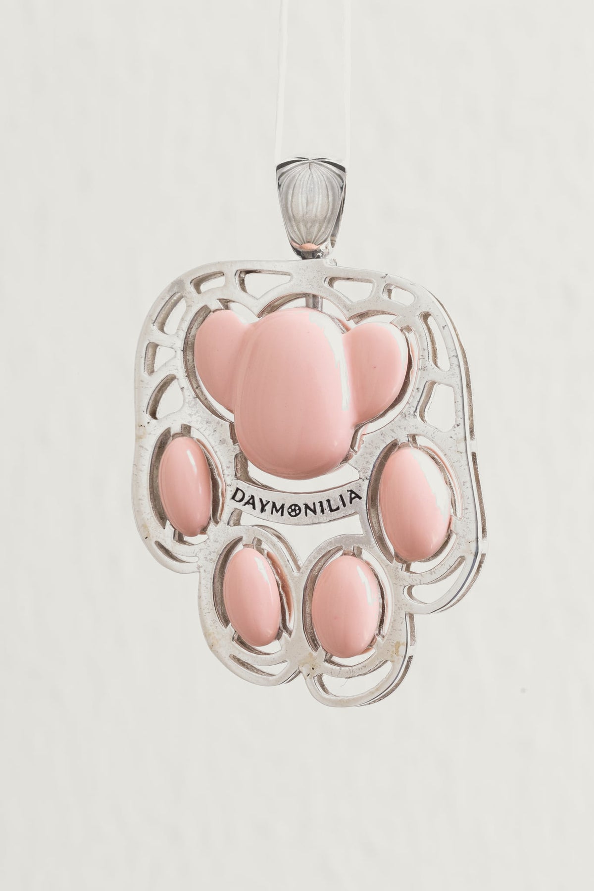 Da vicino i cuscinetti di Palmo: composto vitreo rosa tagliato a mano, nessun cuscinetto uguale all'altro, incastonati nell'argento sopra la fascia incisa Daymonilia.