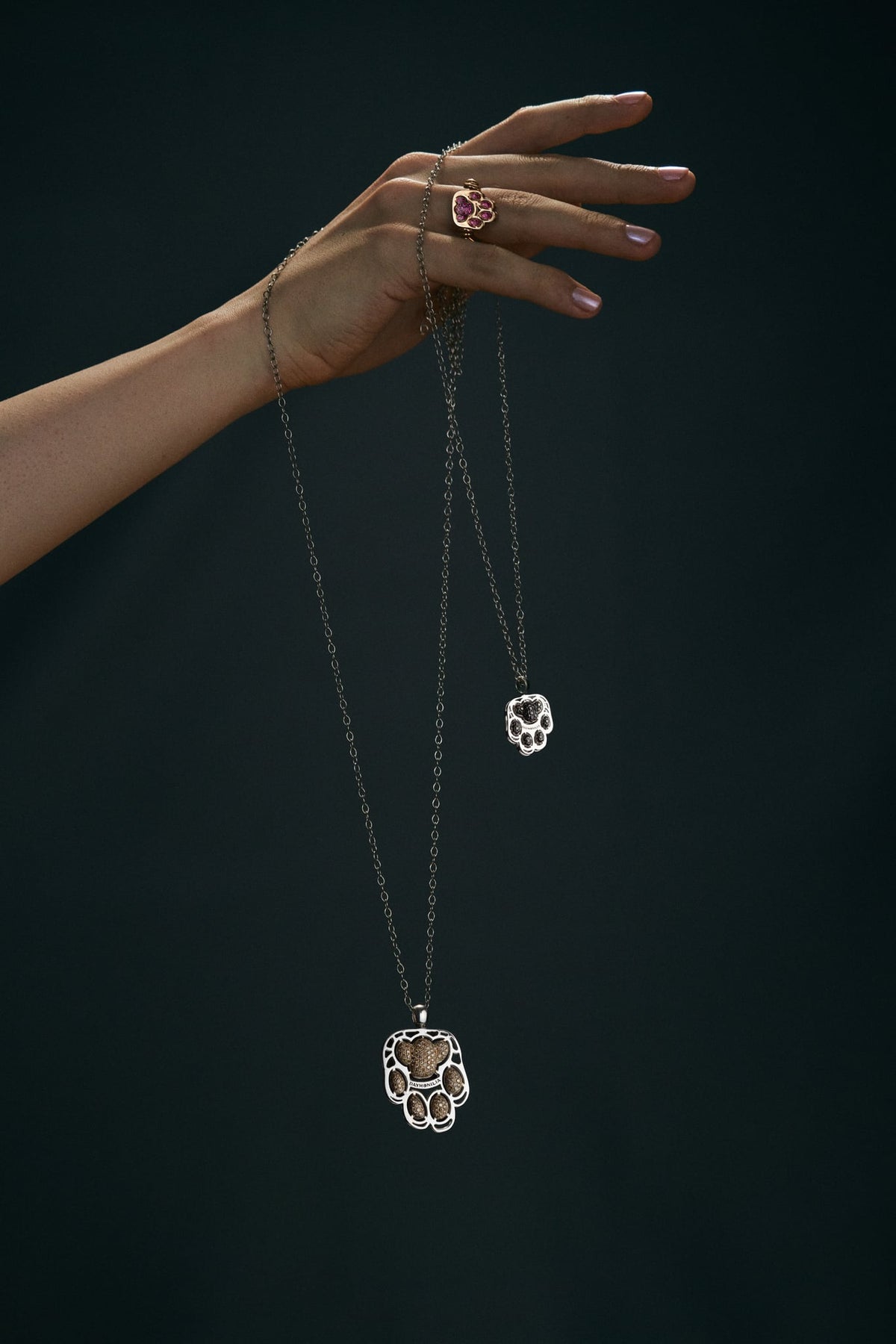 A hand in the dark lets Pardo hang from its chain; Fusa on the ring finger.